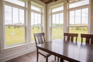 A dining room with table and chairs, and expansive windows with a view to green space
